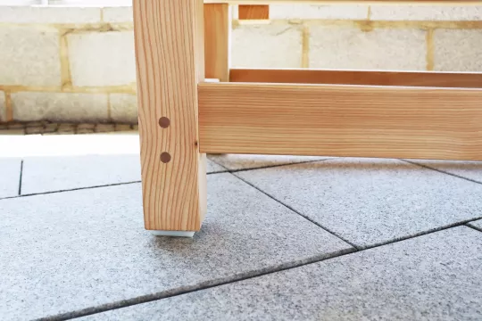 Detailaufnahme Holzgestell einer Gartenbank - Kunststoff-Fußgleiter zum Schutz